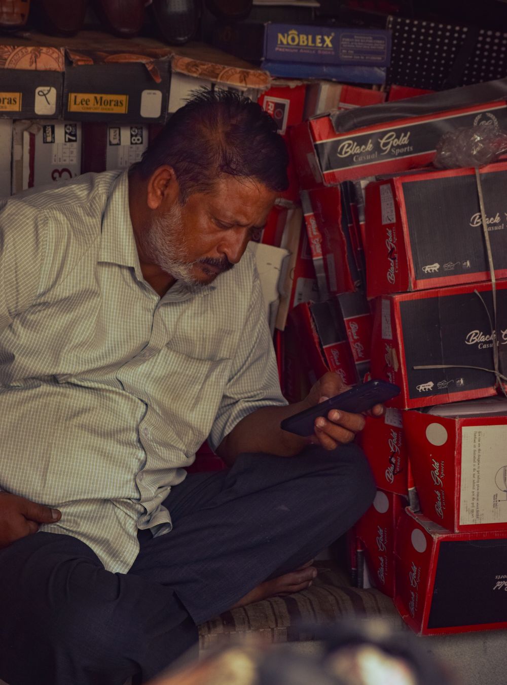An Indian shop owner taking a customer order on his phone