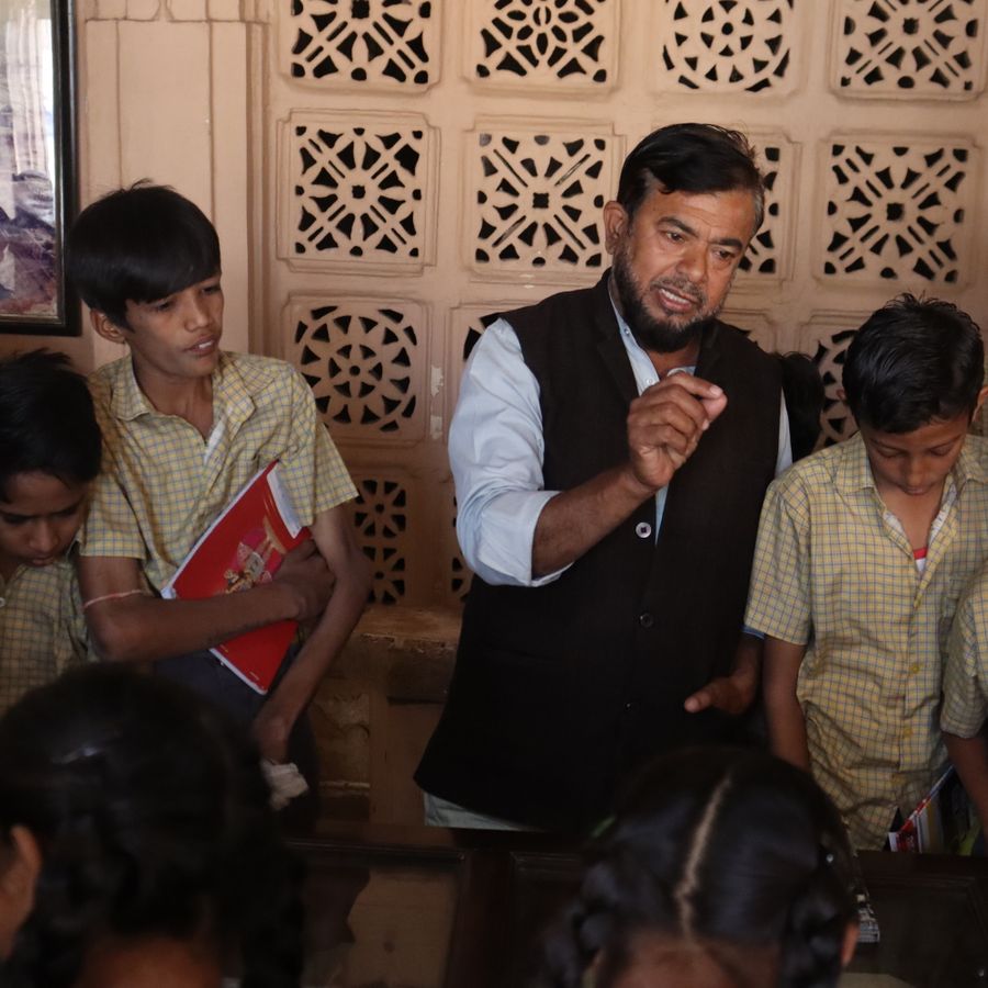 An Indian teacher guiding students in a lively classroom