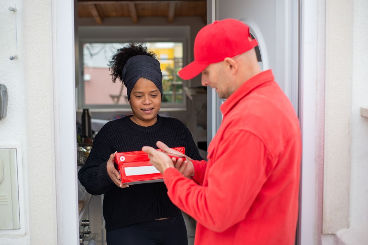 A delivery partner handing an order to a customer in India